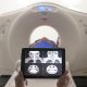 A Patient Undergoing CT Scan While Lab Person Holding A Tablet Showing The Patient's Brain.
