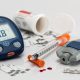 Glucose meter and injections for insulin on a gray background.