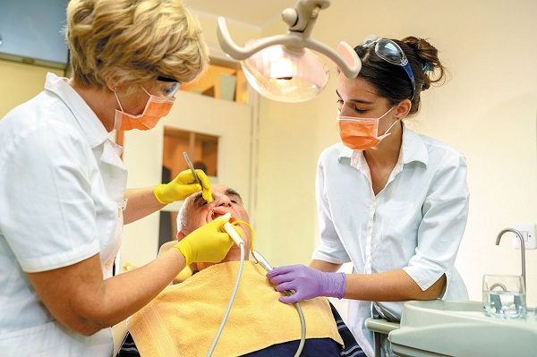 Two Dentists performing their medical procedure to a senior man during his oral health checkup.